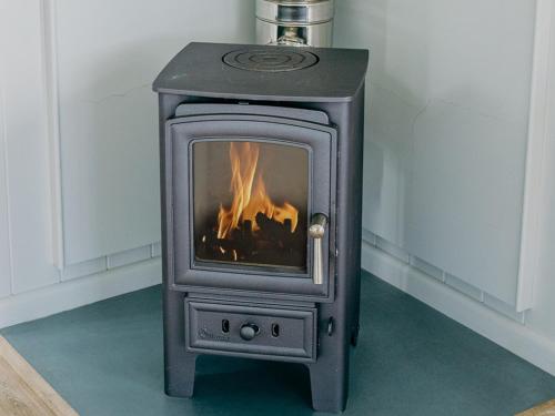 a stove with a fire in a room at Phoebe's Folly-Uk36581 in Milton Abbot