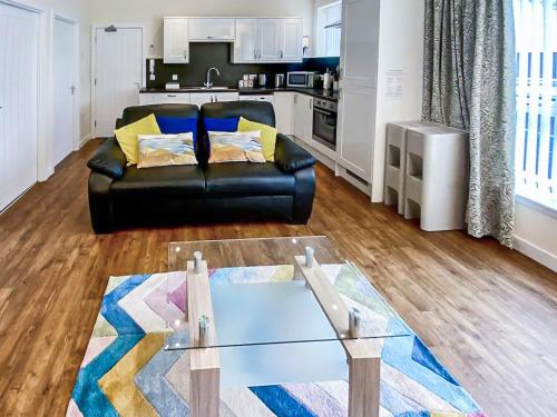 a living room with a black leather couch and a kitchen at Muckle Green Holm - Uk48091 in Kirkwall
