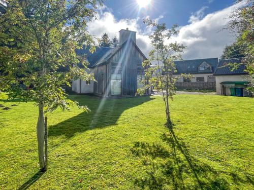 a house in a field with two trees at River View in Dalwhinnie