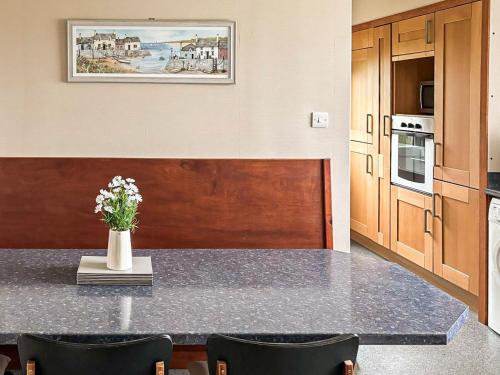 a kitchen with a table with a vase of flowers on it at Havrock in Kirkwall