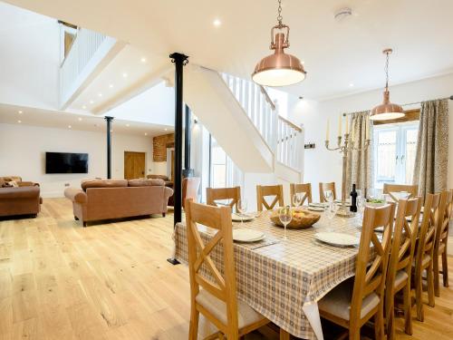 a dining room and living room with a table and chairs at Pipistrelle Barn in North Walsham