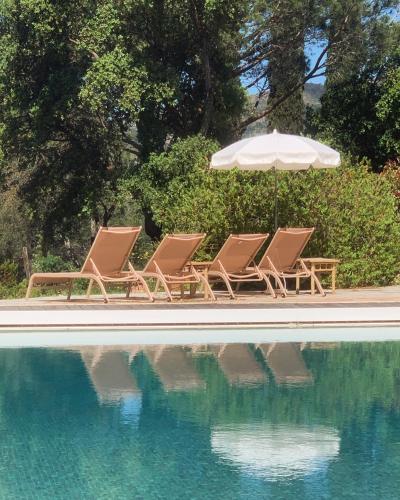 two lounge chairs and an umbrella next to a swimming pool at Hôtel La Boulangerie in Grimaud