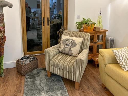 un salon avec une chaise avec un oreiller de chien dans l'établissement Little Barn - Cottage, à Holsworthy