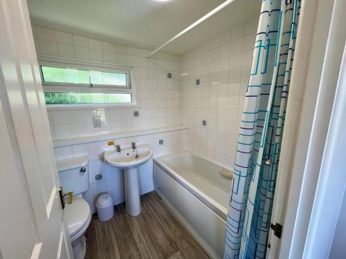 ein Badezimmer mit Toilette, Waschbecken und Badewanne in der Unterkunft Beach Cottage 6 - Bright & Modern By the Sea in Westward Ho