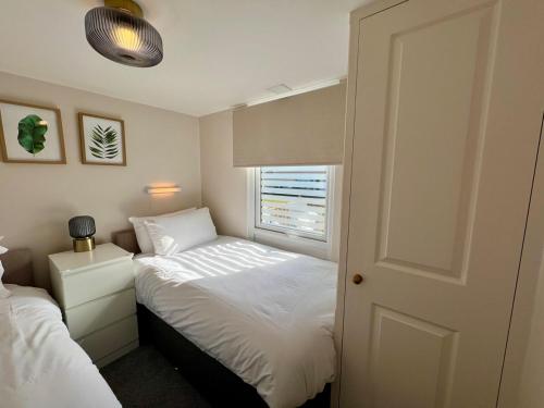 ein kleines Schlafzimmer mit zwei Betten und einem Fenster in der Unterkunft Beach Cottage 6 - Bright & Modern By the Sea in Westward Ho