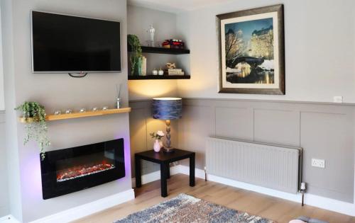 a living room with a fireplace and a flat screen tv at Last-Minute Escape l The Grey Door 2 Bed Cottage Banbridge Parking Private Garden l Nestled Property Management in Banbridge