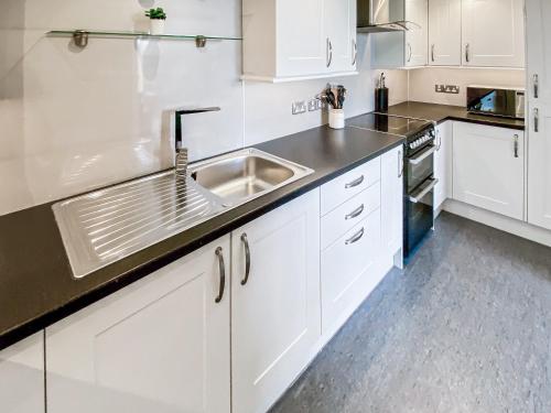 a kitchen with white cabinets and a sink at Broad Apartment 7 - Uk48073 in Kirkwall