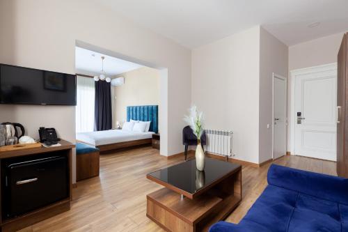 a living room with a blue couch and a bed at Gelati Residence in Kutaisi