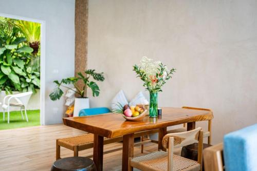 a dining room table with a bowl of fruit on it at The Rock Samui Beachfront Villas - Sha Plus Hotel in Lamai