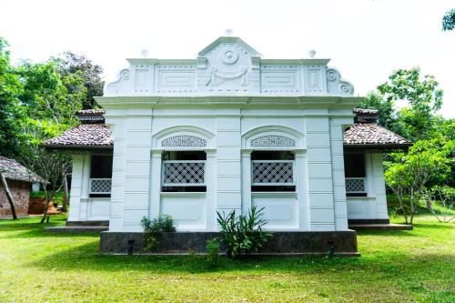 a small white building in a field of grass at Villa Kobeimalhéna, Matara in Sulutanagoda
