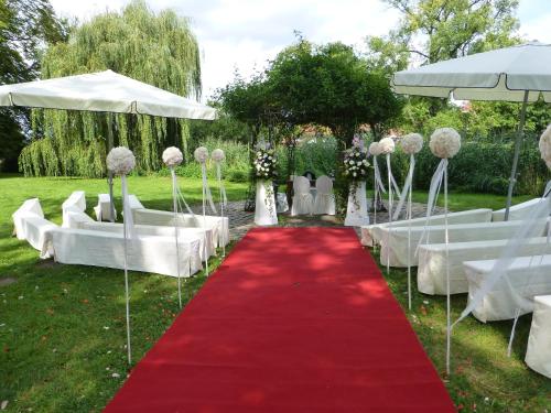 a red and white wedding aisle with white chairs and a red carpet at Schloss Diedersdorf in Diedersdorf