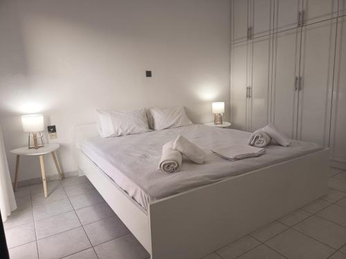 a white bedroom with a large white bed with two pillows at George Arhagelos Villa in Archángelos