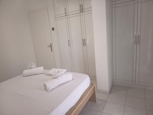 a white bedroom with two towels on a bed at George Arhagelos Villa in Archángelos