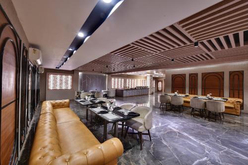 a restaurant with a long couch and tables and chairs at RnB Select Walk Inn Lucknow in Lucknow