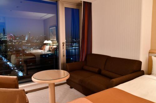 a living room with a couch and a large window at Hotel New Grand in Yokohama