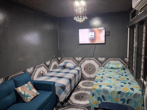 Una habitación con dos camas y un sofá y un televisor. en Mini apartamento familiar, en San Salvador