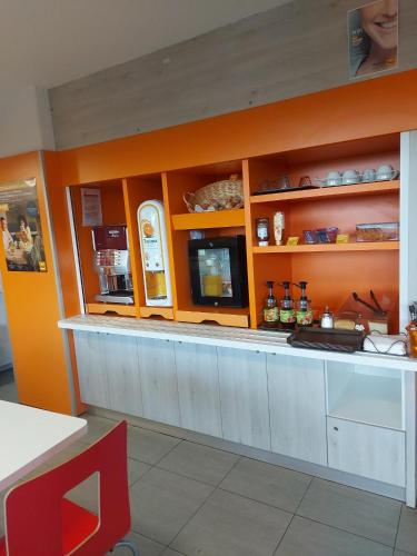 a kitchen with orange walls and a counter in a restaurant at Premiere Classe Arras - Tilloy Les Mofflaine in Tilloy-lès-Mofflaines