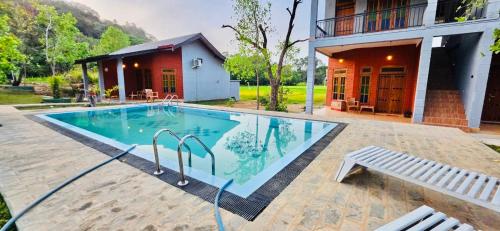 a swimming pool with a bench next to a house at Maapagala Resort Sigiriya in Sigiriya
