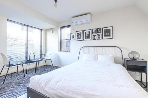 a white bedroom with a bed and a table and chairs at DM Hotel in Tokyo