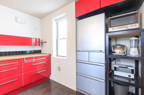 a red and white kitchen with red cabinets at DM Hotel in Tokyo
