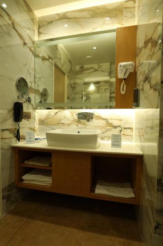a bathroom with a sink and a large mirror at Hotel Blueivy Anand in Anand