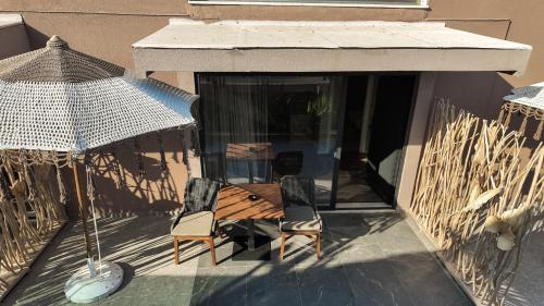 a patio with two chairs and a table and an umbrella at Hotel Platinium Dhermi in Vlorë