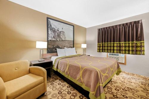 una habitación de hotel con una cama y una silla en Super 8 by Wyndham Blue Earth, en Blue Earth