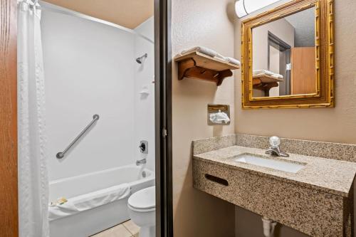 Un baño con lavabo, inodoro y espejo. en Super 8 by Wyndham Blue Earth, en Blue Earth