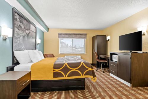 a hotel room with a bed and a desk at Super 8 by Wyndham Osseo WI in Osseo