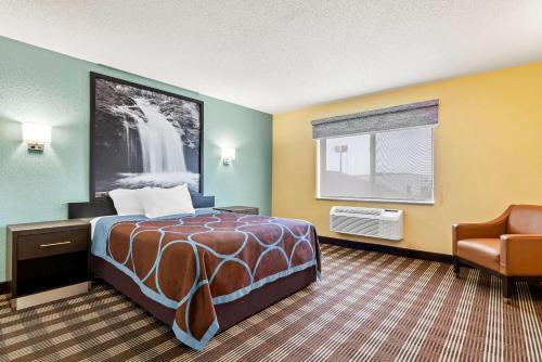 a hotel room with a bed and a chair at Super 8 by Wyndham Osseo WI in Osseo