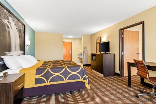 a hotel room with a bed and a desk at Super 8 by Wyndham Osseo WI in Osseo