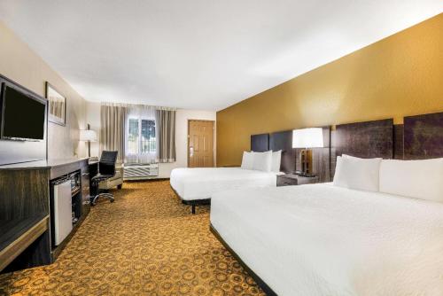 a hotel room with two beds and a flat screen tv at Baymont by Wyndham Cortez in Cortez