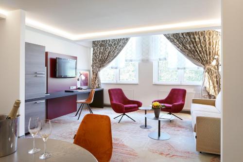 a living room with red chairs and a table at Best Western Plus Arosa Hotel in Paderborn