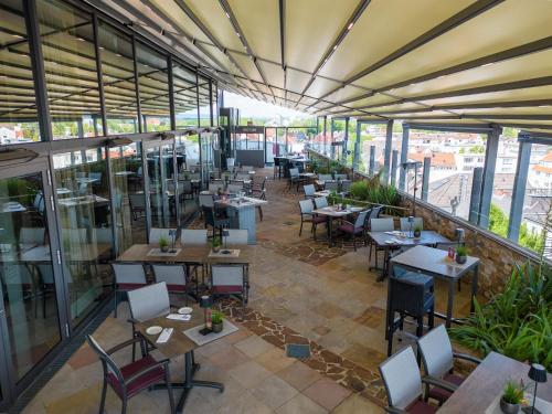 an empty restaurant with tables and chairs and windows at Best Western Plus Arosa Hotel in Paderborn