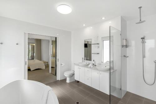 a white bathroom with two sinks and a shower at Blanco at Island Views—Beautiful Beachfront Living in Palm Cove