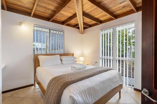 マーガレットリバーにあるTerrace Haus Margaret Riverの白いシーツと窓のあるベッドのある寝室