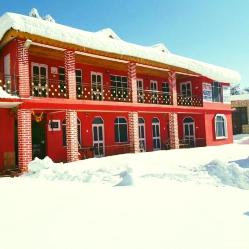 a red building with snow in front of it at The Velvet Pine in Chamba