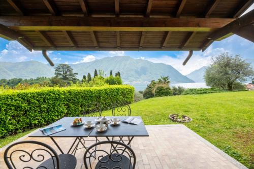 a table and chairs on a patio with mountains in the background at Antica Isola Giardino - Happy Rentals in Sala Comacina