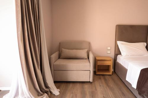 a bedroom with a bed and a chair next to a window at Hotel Platinium Dhermi in Vlorë
