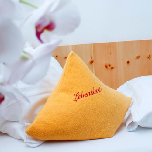 a pillow with the word klezmer on it next to flowers at Hotel Erlebniswelt Stocker in Schladming