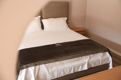 a bed with white sheets and a black blanket at Hotel Platinium Dhermi in Vlorë