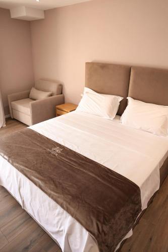 a bedroom with a large bed and a chair at Hotel Platinium Dhermi in Vlorë