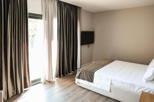 a bedroom with a bed and a large window at Hotel Platinium Dhermi in Vlorë
