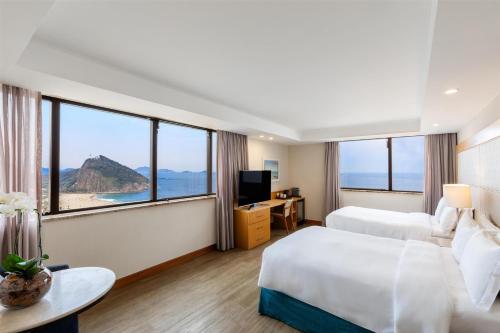 a hotel room with two beds and large windows at Hilton Copacabana Rio de Janeiro in Rio de Janeiro