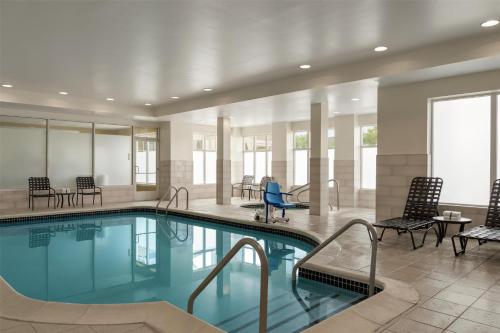 a pool in a hotel room with chairs and tables at Hilton Garden Inn Allentown Bethlehem Airport in Allentown