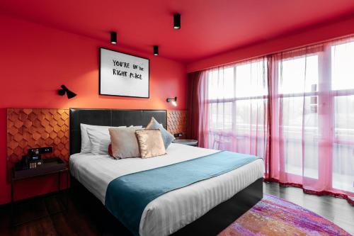 a bedroom with red walls and a large bed at Naumi Auckland Airport Hotel in Auckland
