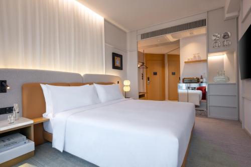 a bedroom with a large white bed and a living room at Mondrian Hong Kong in Hong Kong