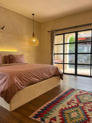 a bedroom with a bed and a window and a rug at El Campo Mushroom in Nusa Lembongan