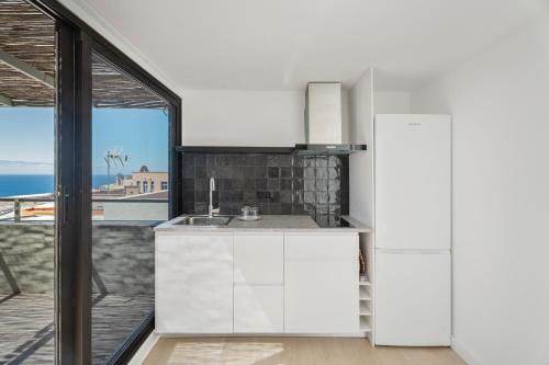a kitchen with white cabinets and a view of the ocean at Nomad Hub Tenerife in Barranco Grande