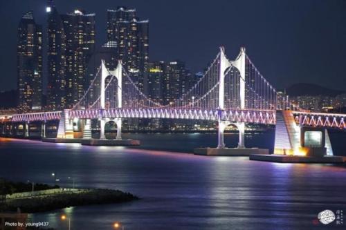 a lit up bridge over the water at night at Gwangan The L in Busan